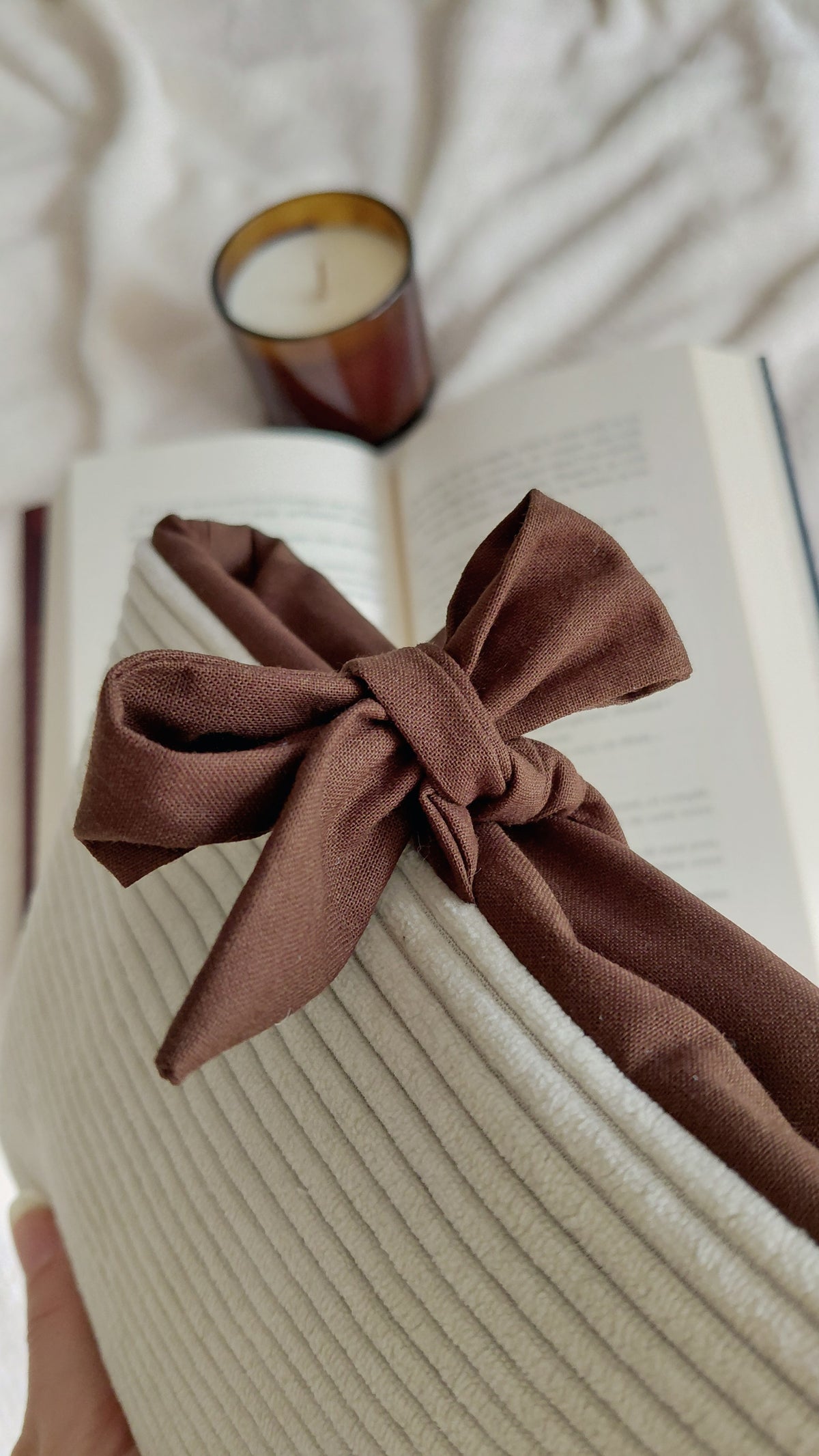 Pochette à livre format poche de la collection automne. Exterieur en velours côtelé écru et intérieur en coton couleur chocolat. Molletonnée, elle est parfaite pour emmener ses lectures partout avec soi sans les abîmer.